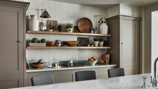 An example of how to make a small kitchen look bigger showing kitchen shelving displaying crockery and vases between cabinetry opposite a marble-topped island