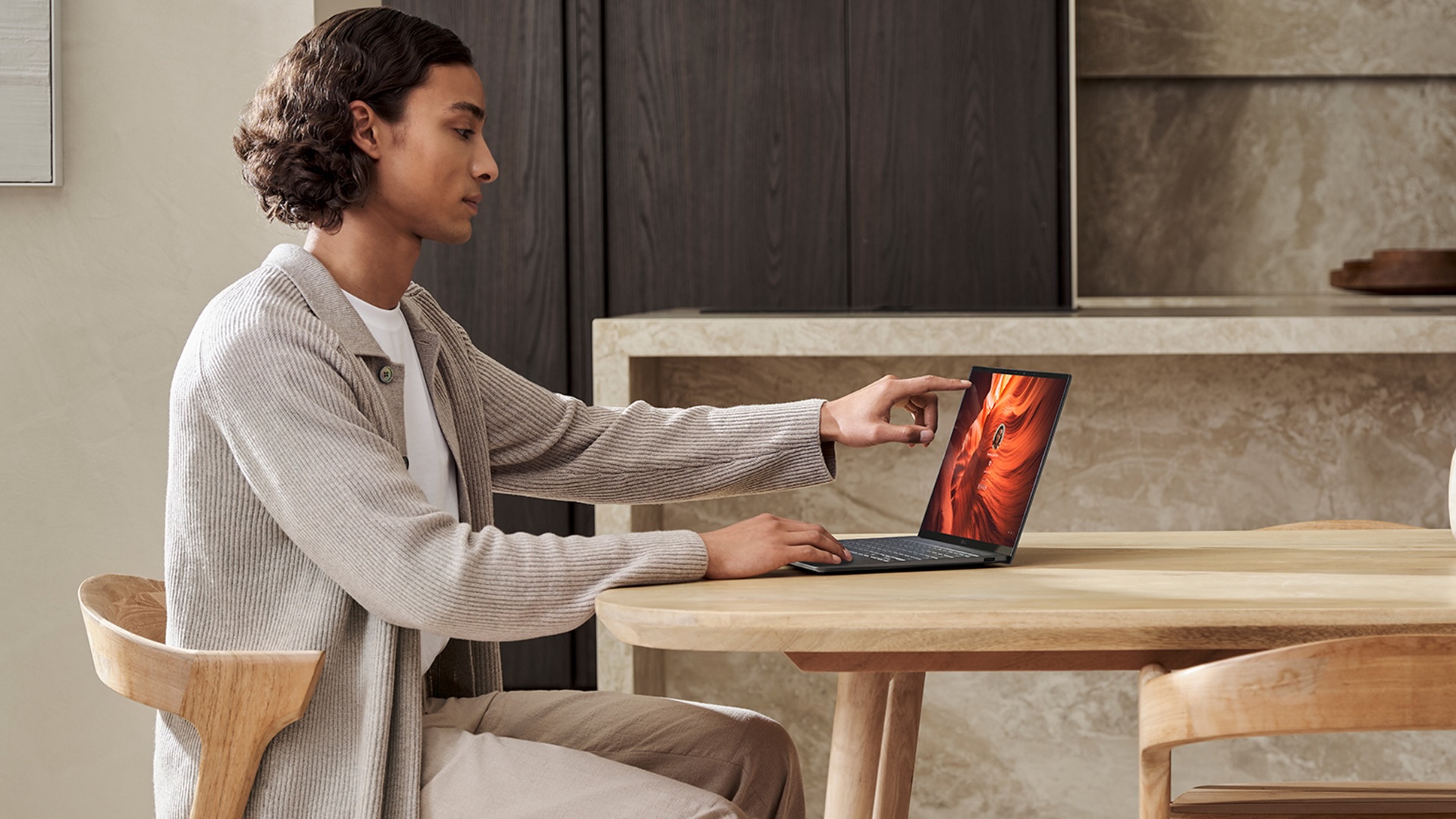 A person using an Intel Core Ultra Series 3 laptop at a wooden table in a neutrally decorated room