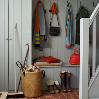 A hallway with grey wood wall panelling and a matching storage wardrobe and bench