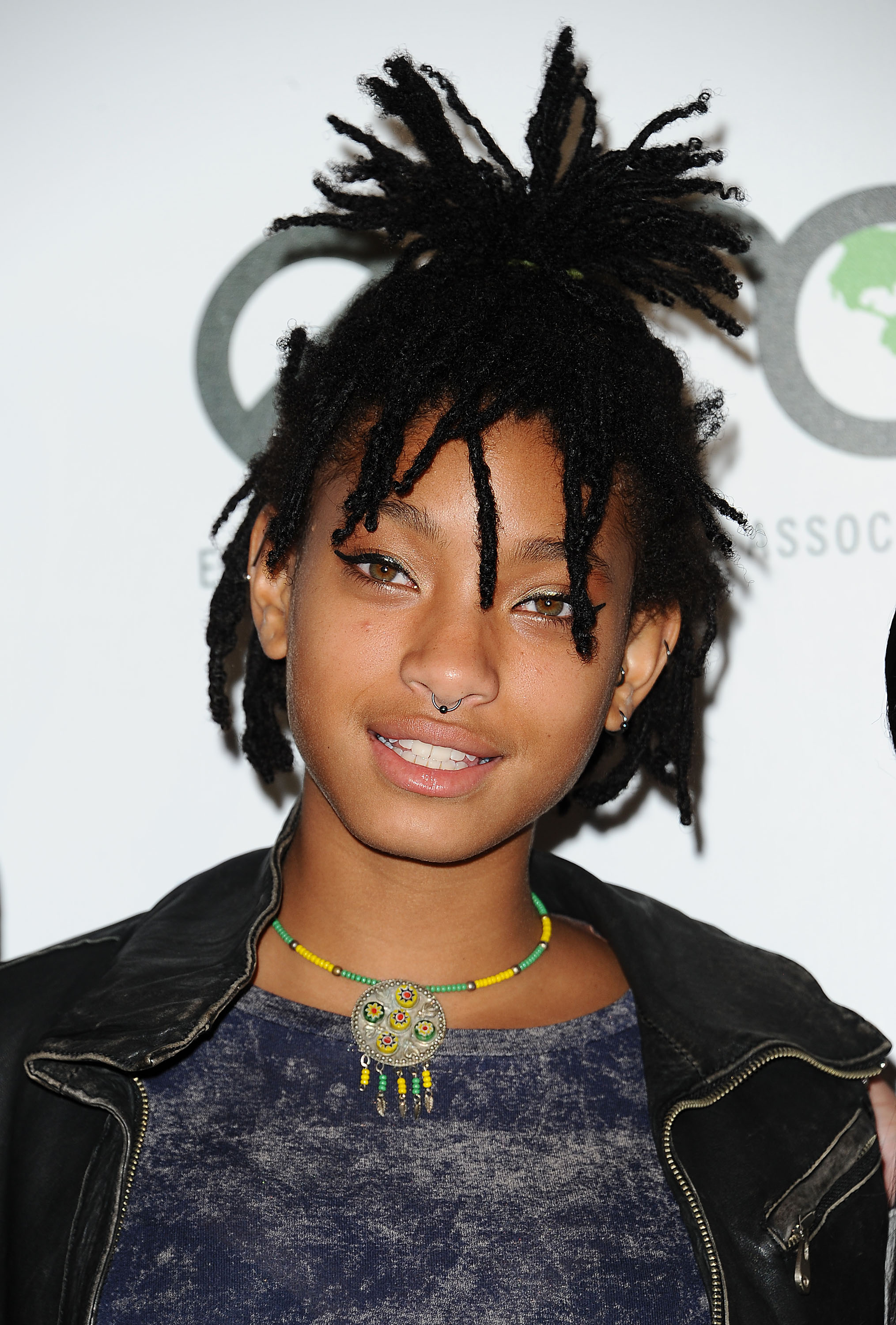 a young black woman wearing a high, half up ponytail with a black blazer in front of a white background