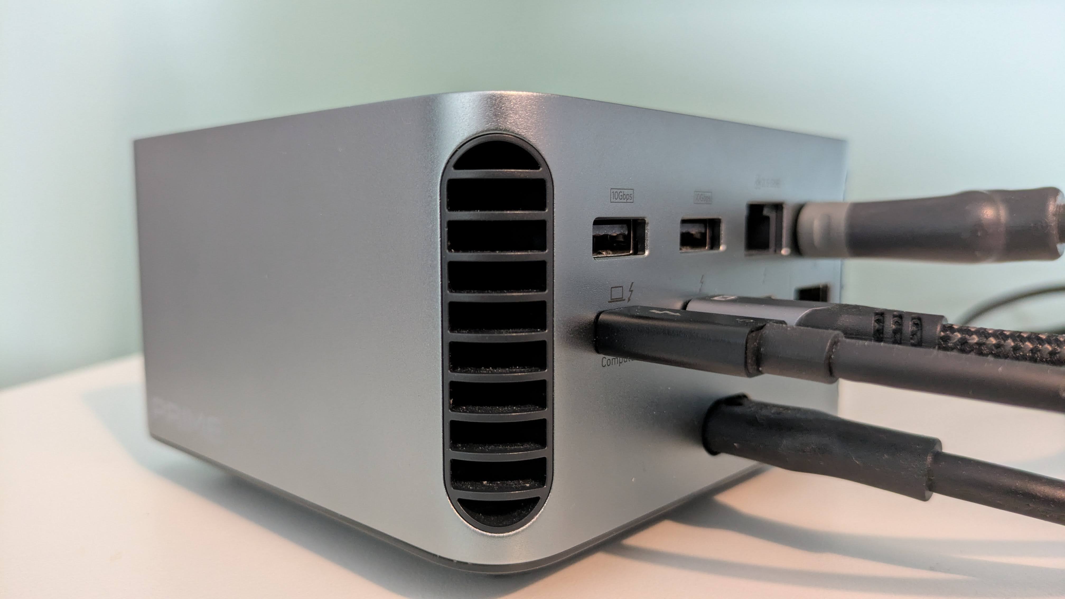 Rear three-quarter view of Anker Prime Docking Station (14-in-1, 8K, Thunderbolt 5) with various cables attached, on desk with green background