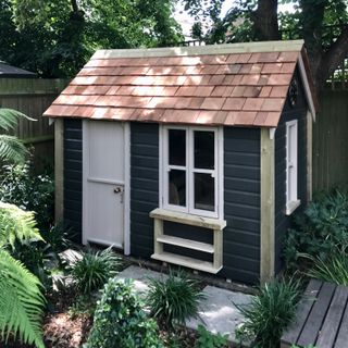 shed garden room with black cladding and white door and tiled roof
