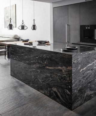 A black kitchen idea with large black marble island and black cabinets