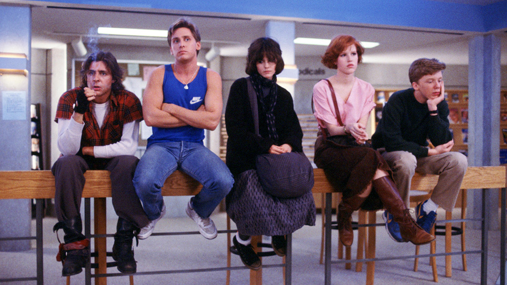 A still from the movie The Breakfast Club in which all of the main characters sit on stools.