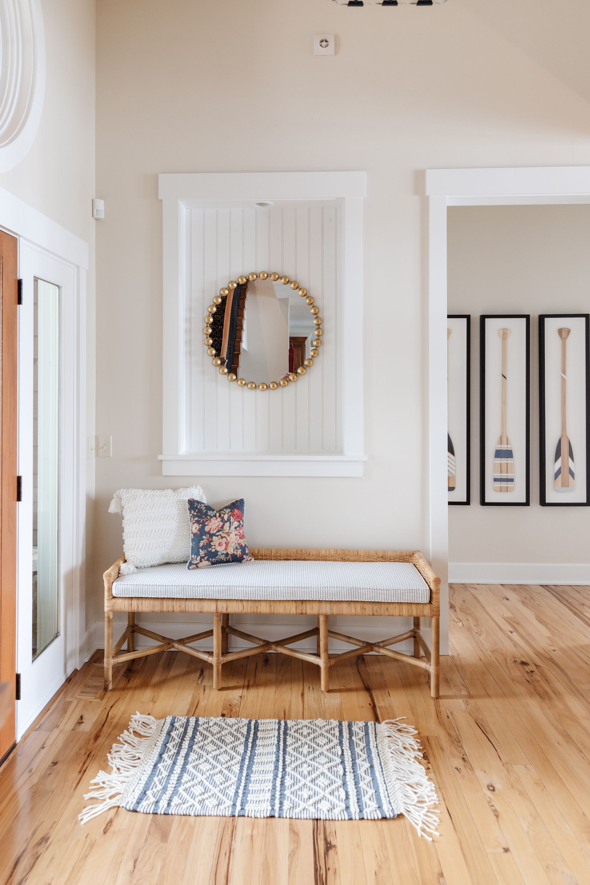 Entryway with wood floor and area rug, bench and mirror with neutral walls