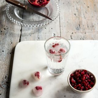 table with chopping tray and pomegranate and glass