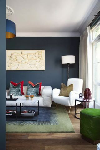 Living room with dark blue walls white sofa and colorful furniture