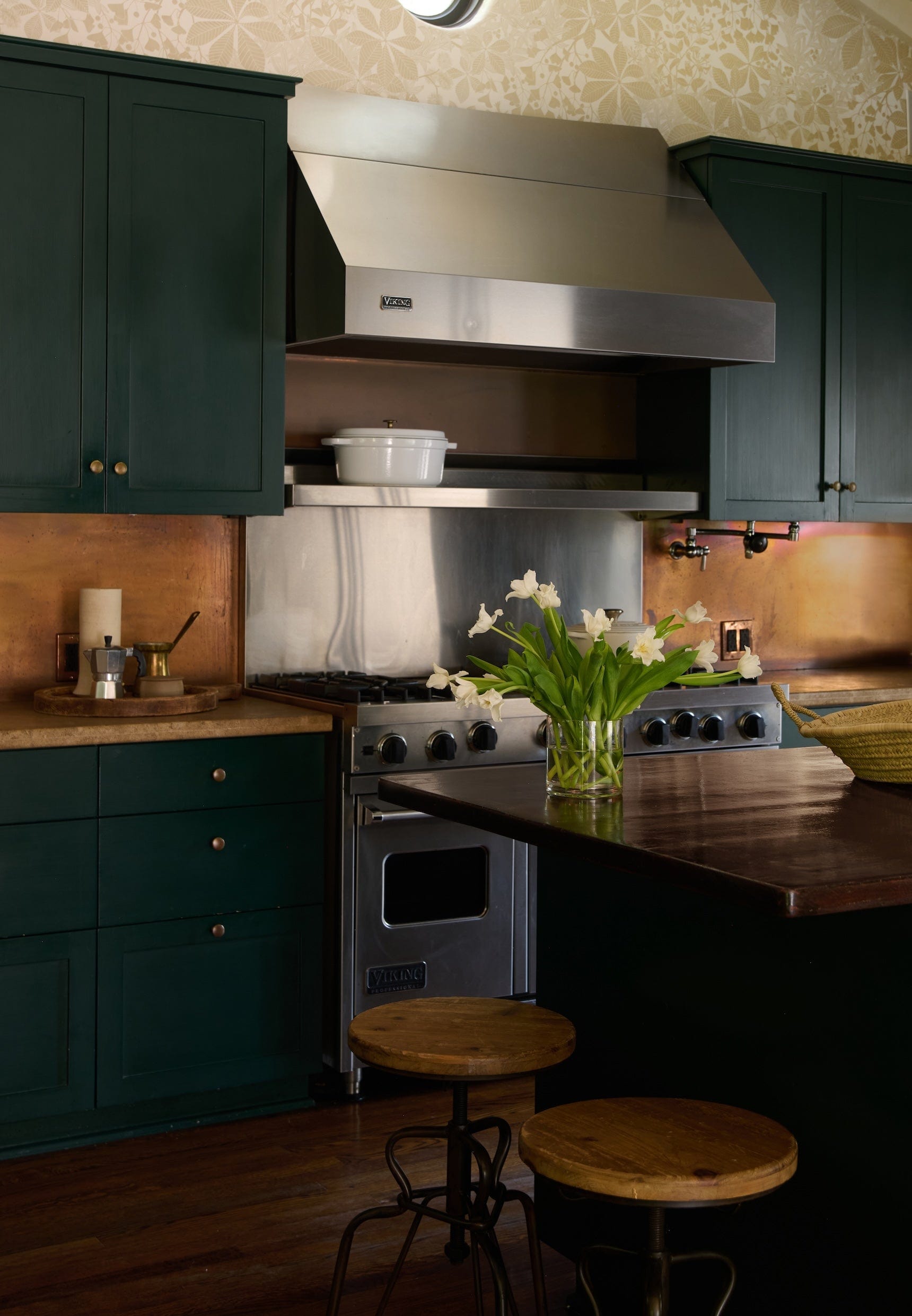 blue kitchen cabinets with bronze backsplash and large silver range cooker in the middle.