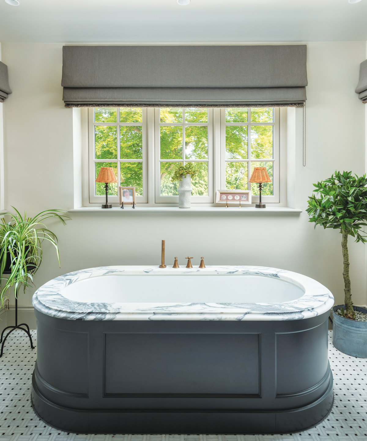 bathroom with freestanding bath underneath window with grey panelled sides and marble top