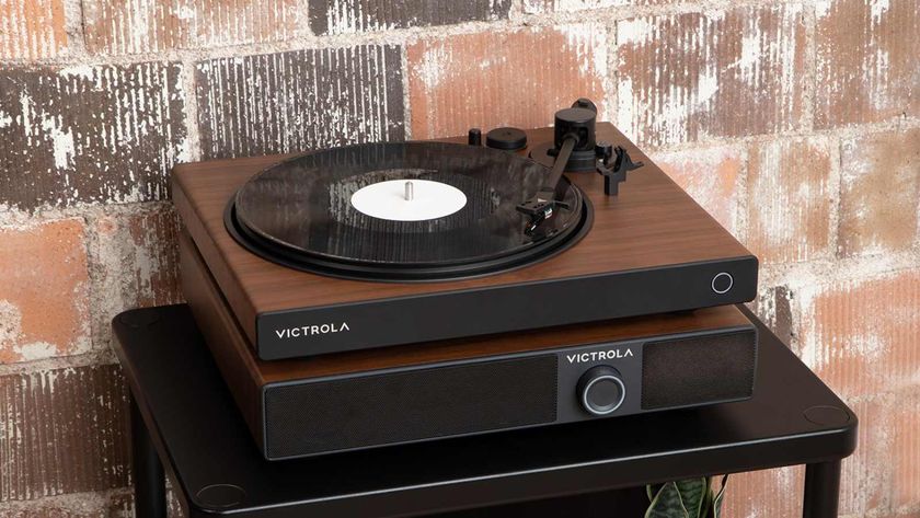 The Victrola Soundstage under a Victrola turntable, on a table by a brick wall.