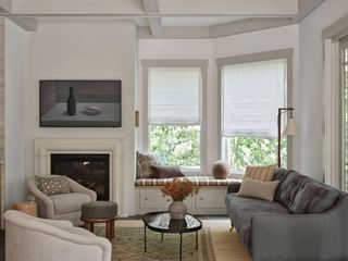 a white living room with a dark gray couch and two armchairs