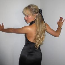 Instagram image of Sabrina Carpenter posing in a black dress and a half-up half-down hairstyle.