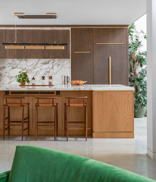 a marble and wood kitchen with a linear pendant light