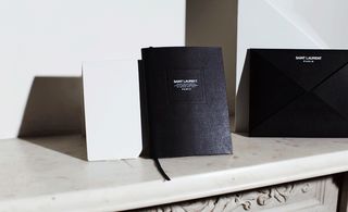 White marble mantelpiece, black art booklet invitation with black envelope