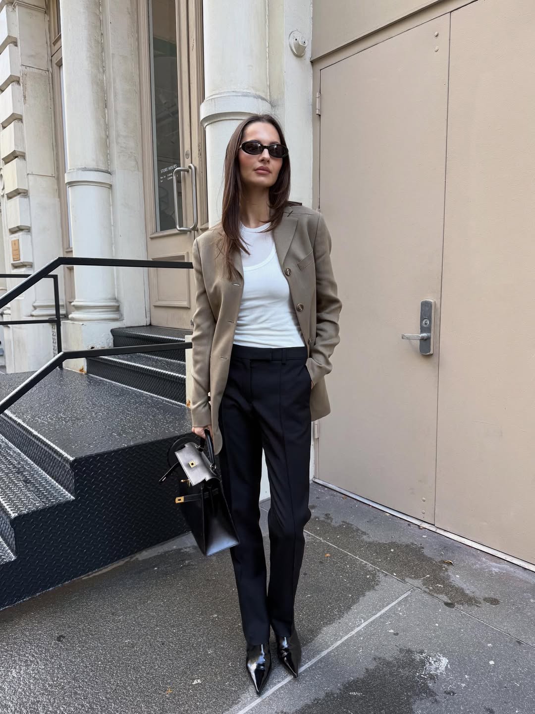 A woman wearing a beige blazer, leather boots, and black pants.