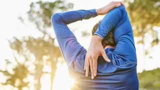 Why do muscles get sore after exercise? Image shows man stretching