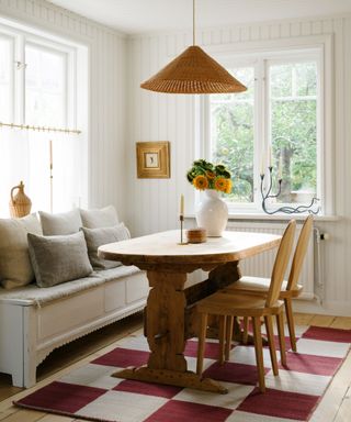 woden bench seat in a kitchen with a small antique table and a red and white checkerboard rug