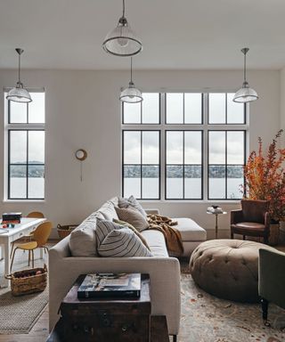 living space overlooking water with large white sofa and brown pouf