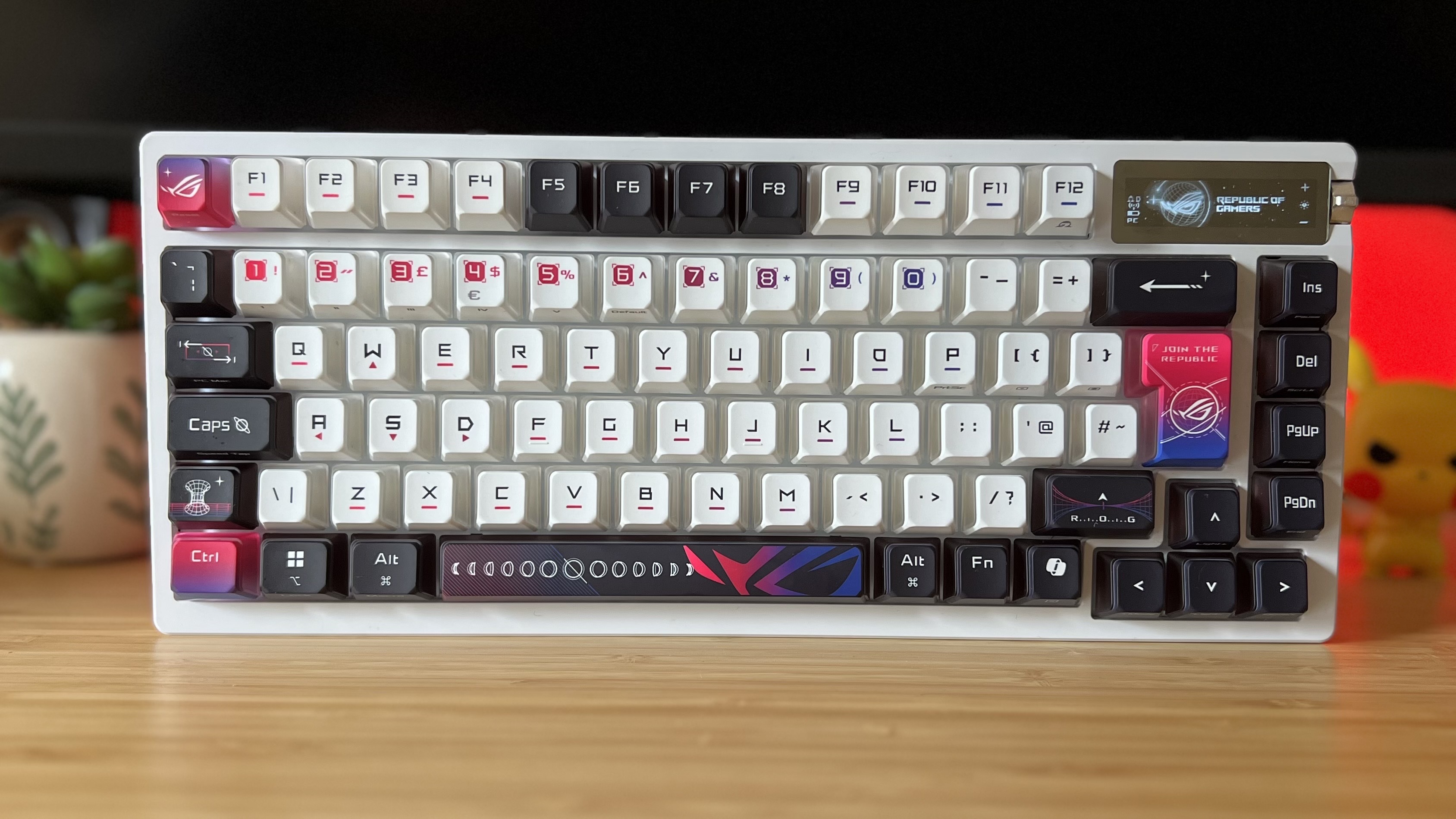 Asus ROG Azoth X gaming keyboard on a wooden desk with red backlight