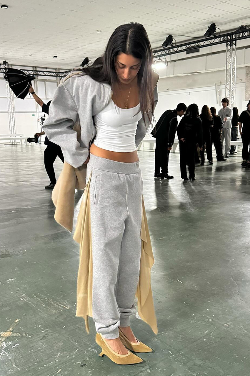 a woman wearing a gray sweatsuit, white tank top, tan heels