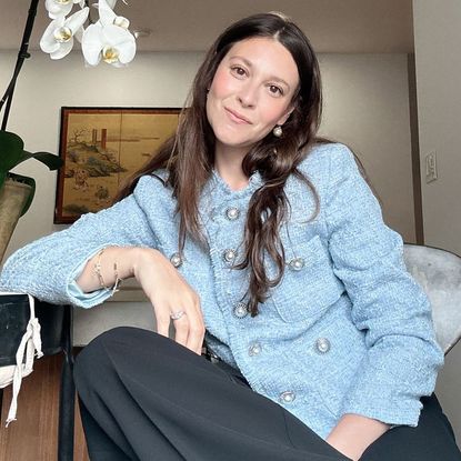 style director sara holzman poses in a blue tweed jacket and black pants