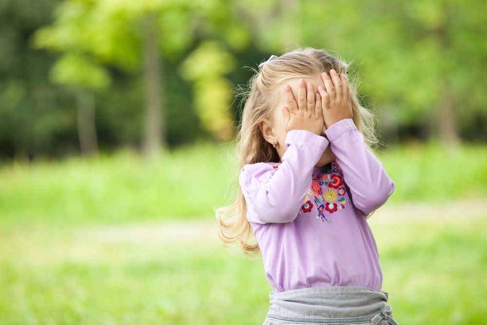 little girl covering her face with her hands