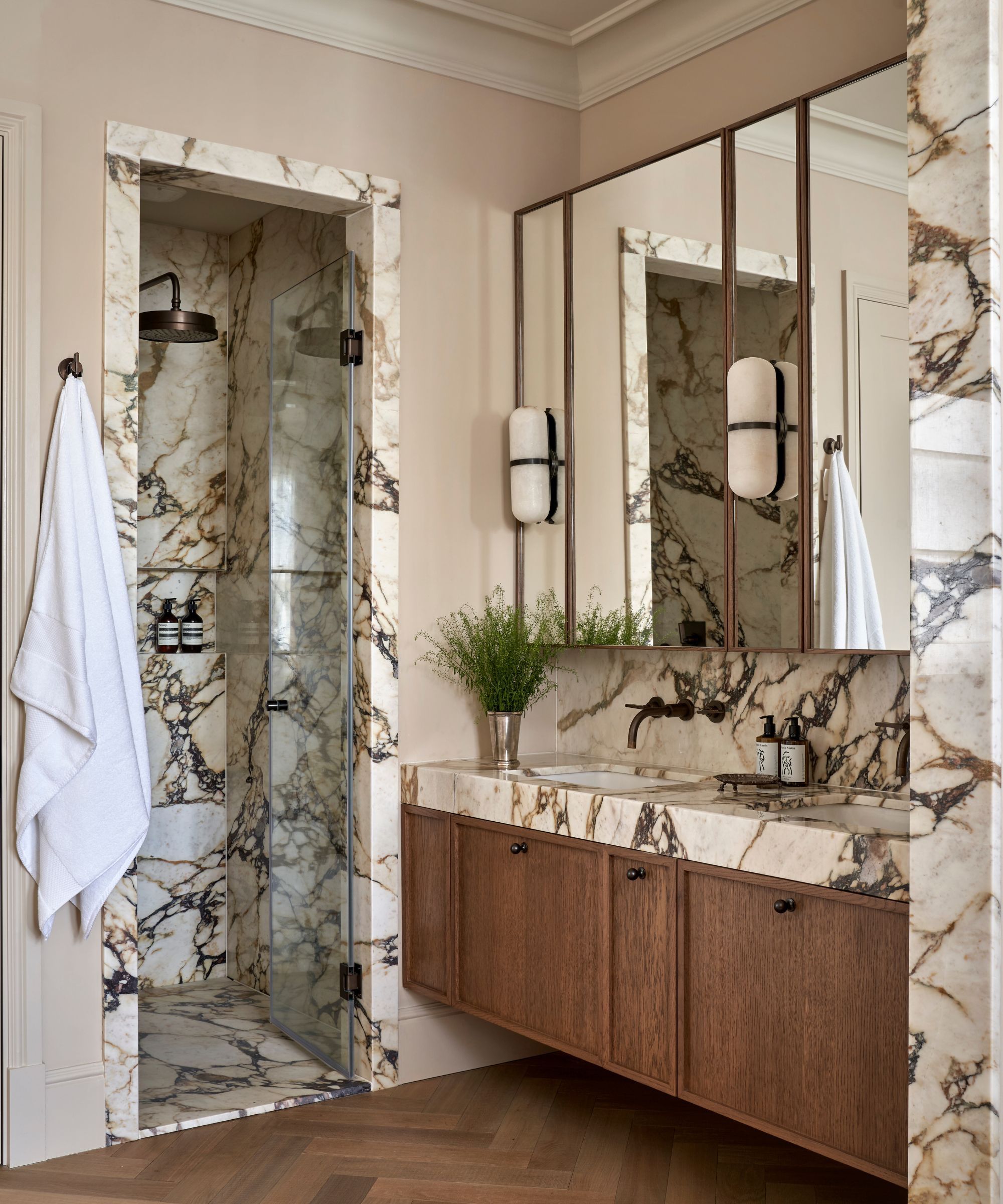 A marble drenched bathroom with a wood vanity