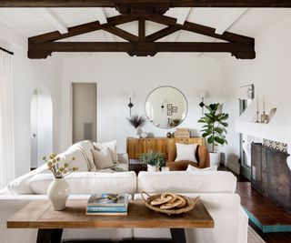 A California modern living room with neutral walls, a white sofa, and exposed wooden ceiling beams
