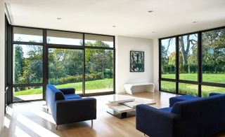 Blue sofas looking out of large windows into wildlife