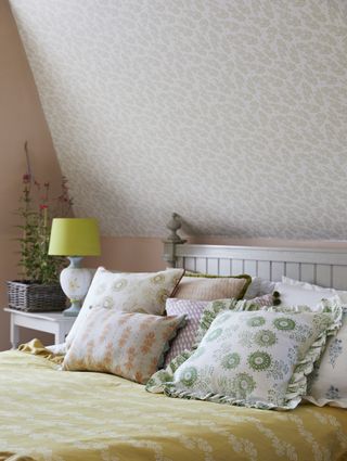 country bedroom with wallpaper behind bed and on ceiling