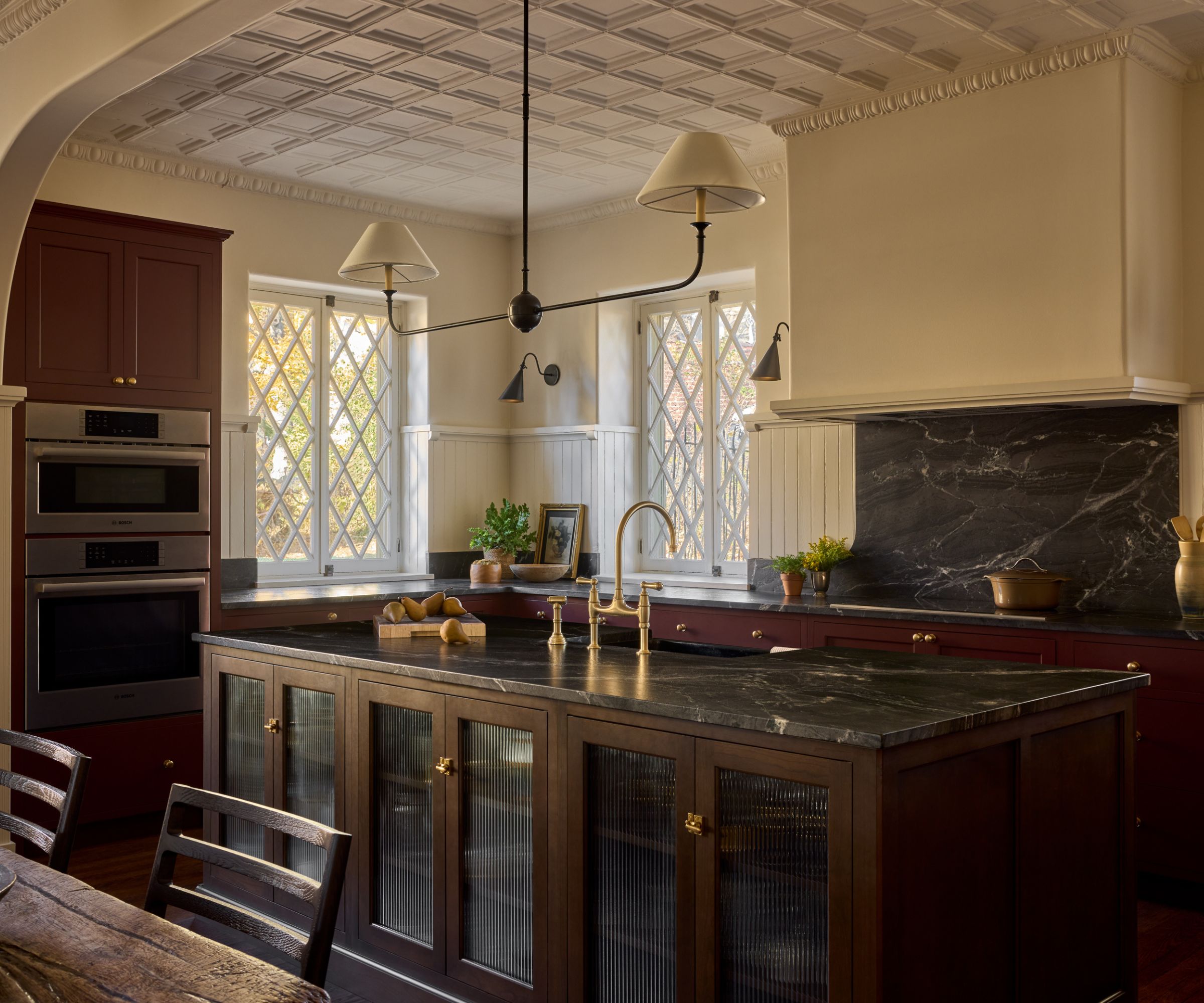 Open plan kitchen and diner with red cabinets and cream walls with dark countertop and a dark wooden island