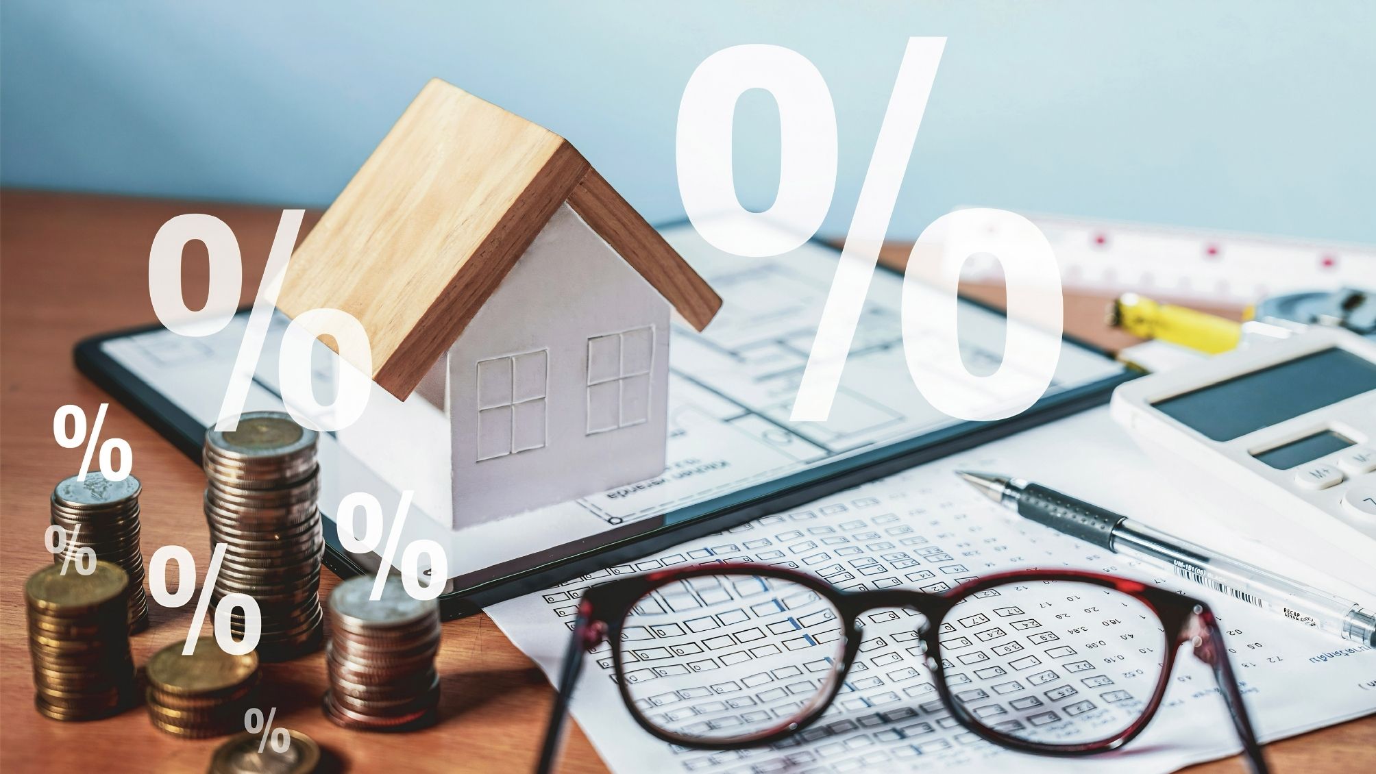 A model house sitting on top of a stack of real estate papers, next to coins and eye glasses.