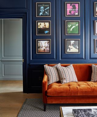 Living room with blue painted paneled walls and orange couch