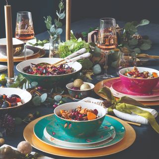 Lavish table set with colourful bowls and plates and gold ribbon napkins