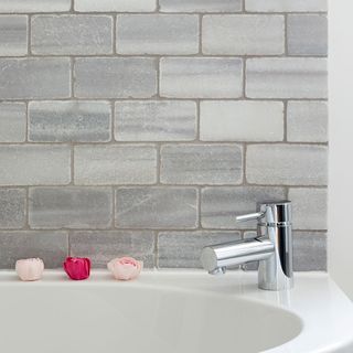 bathroom with grey brick wall and white bathtub