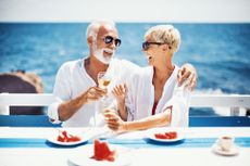 Senior couple toasting with a white wine on the family lunch at beach restaurant.