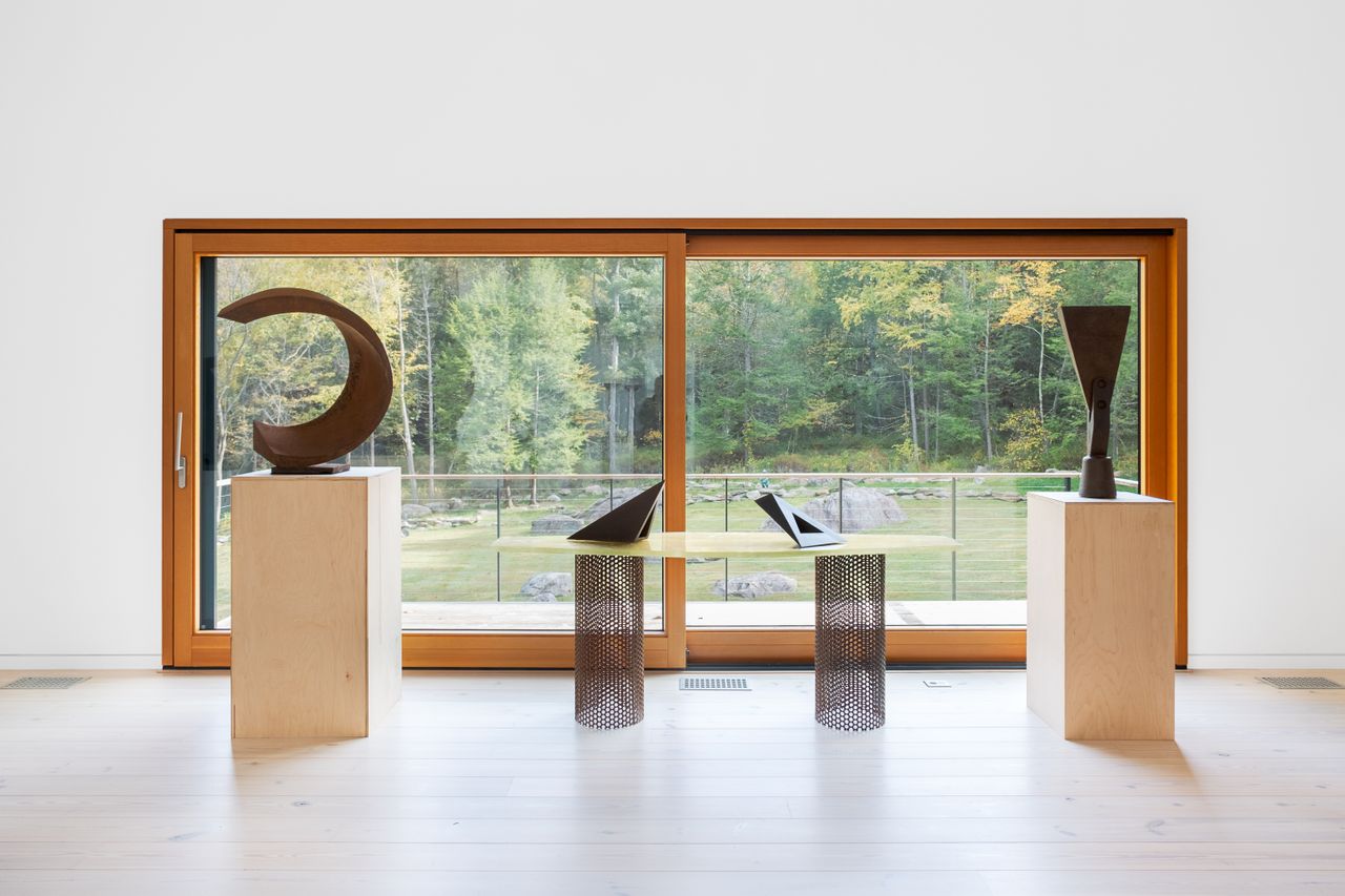 Installation view of a sculptural solo show in a gallery, featuring arched structures carved from copper displayed on white, iron, and beige pedestals in an otherwise white-cube kind of space.