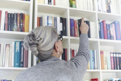 woman taking book off bookshelf