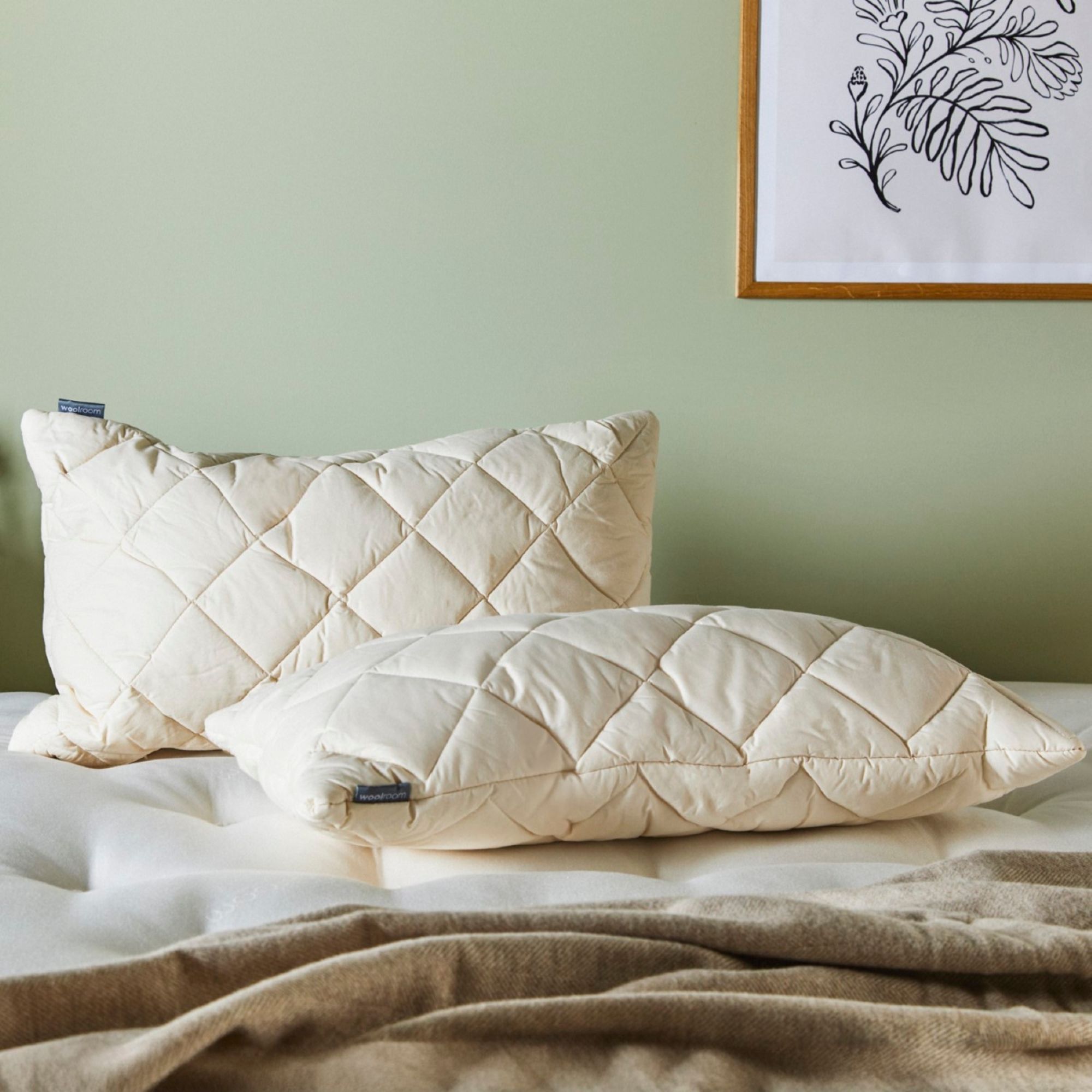 Woolroom pillows on a mattress against a green wall. 