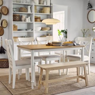 rustic dining room with white table with pine top, benches, wooden floor, open shelving with rustic accessories