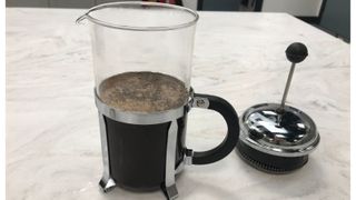 A french press filled with water, but the plunger is off at the side