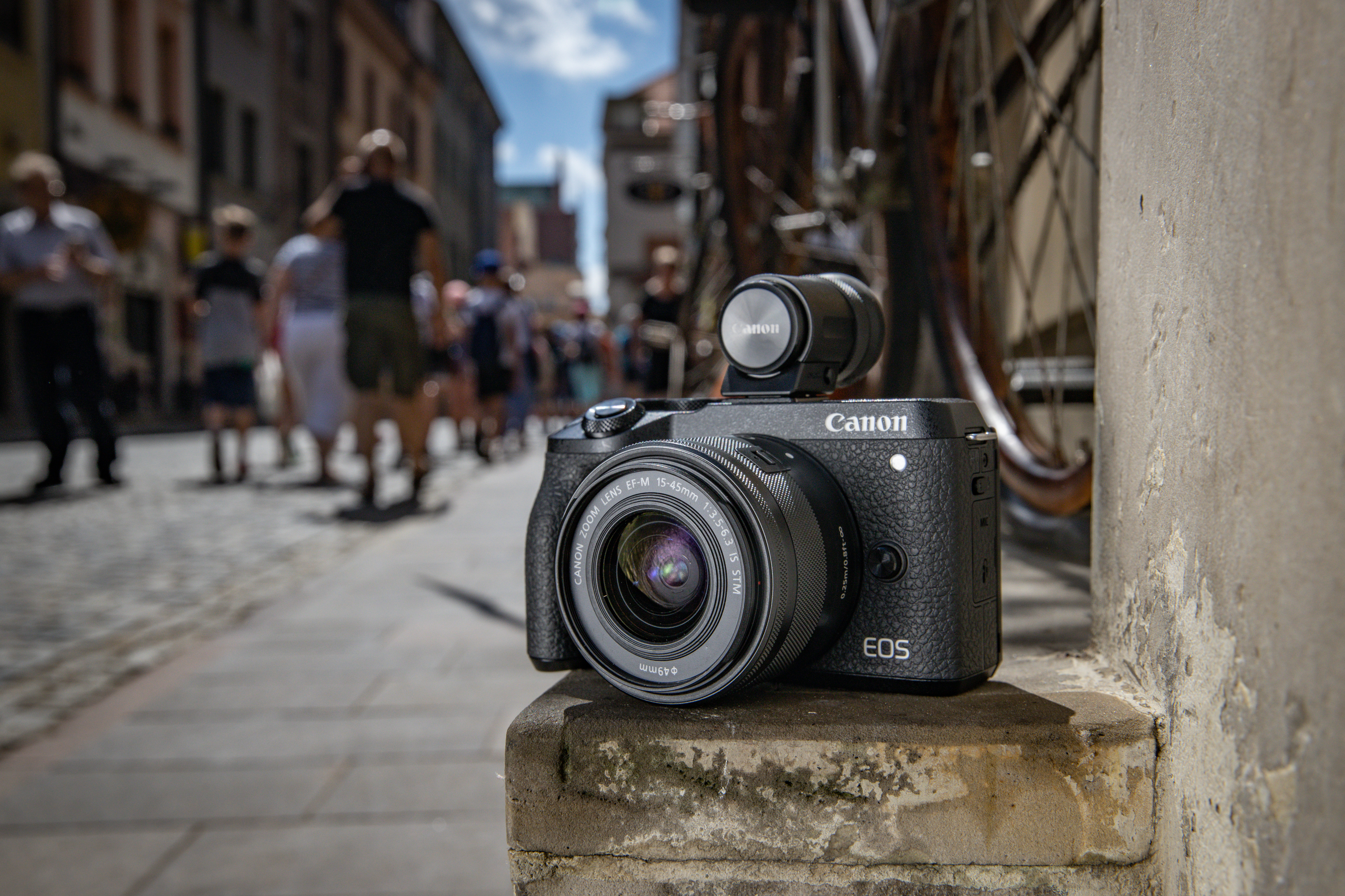 The Canon EOS M6 Mark II with its optional viewfinder sitting on a wall in a street