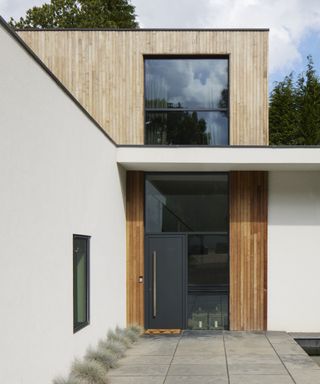 A rendered self build home with vertical larch cladding and a large glass entrance