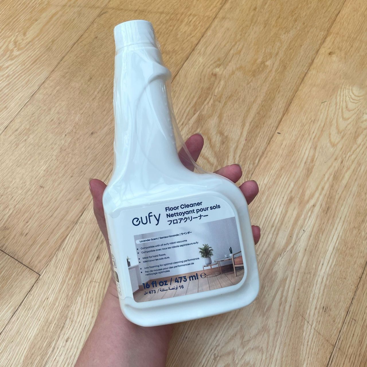Hand holding a bottle of Eufy floor cleaner