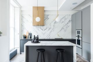 White kitchen ideas with black and marble kitchen island and marble backsplash.