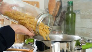 someone pouring pasta from jar to pan