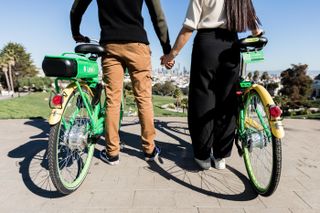 Couple standing beside each other, holding Lime e-bikes