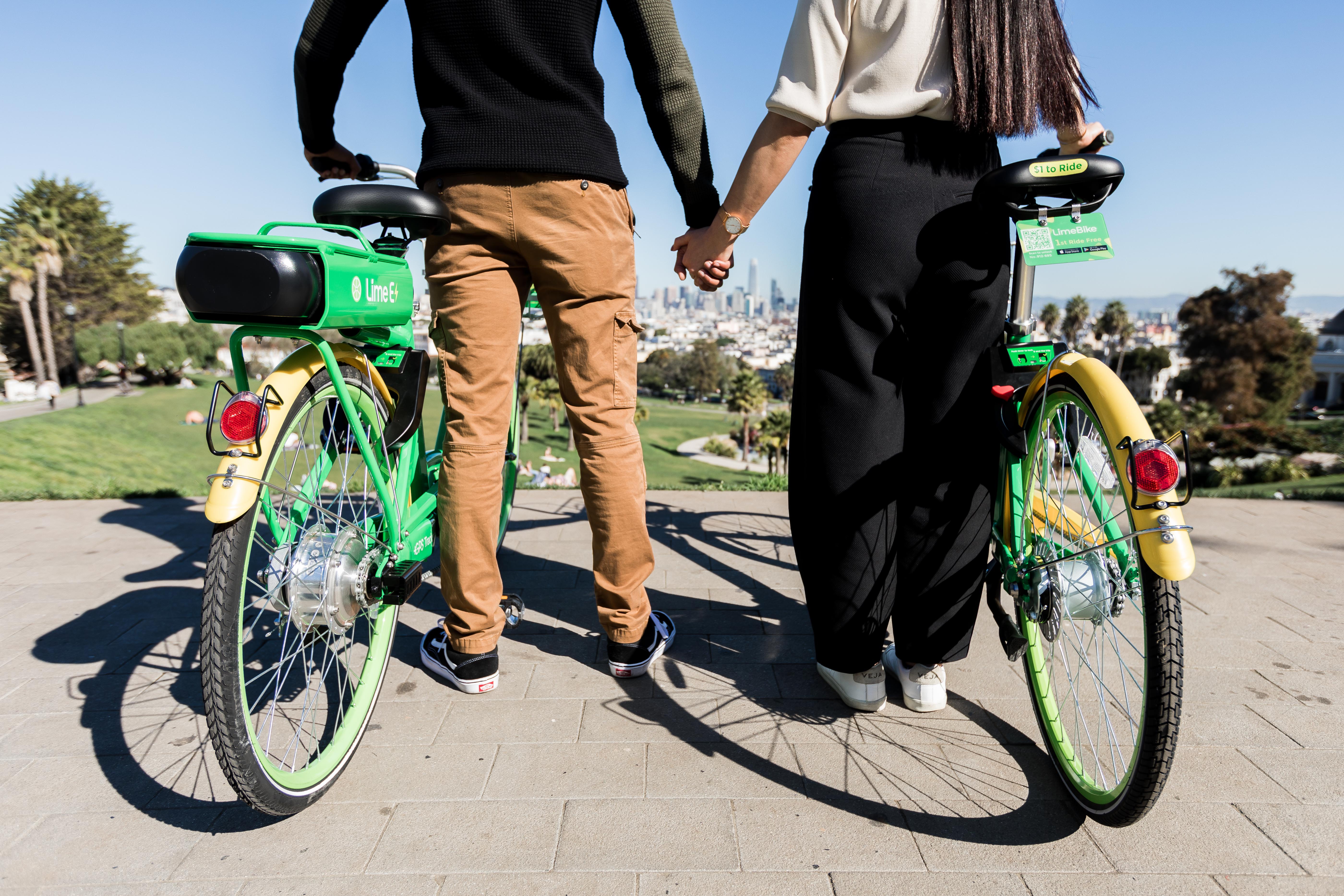 Couple standing beside each other, holding Lime e-bikes