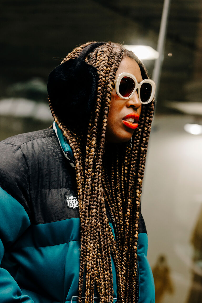 a photo of Leah Faye-Cooper wearing black fuzzy earmuffs and a blue and black puffer coat at new york fashion week