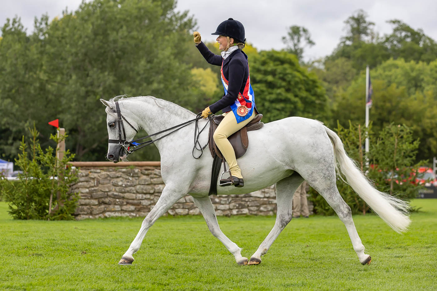 Samantha Taylor waves her hand as Waxwing Perlina shows off her delightful trot in Hickstead&amp;rsquo;s international arena at the Agria Royal International Horse Show.